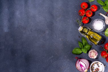 İtalyan yemekleri pişirmek için kullanışlı bir arka plan - domates, fesleğen yaprağı, yeşiller, zeytin yağı, tuz, biber, sarımsak, düz siyah beton masa üstü görünüm alanı 