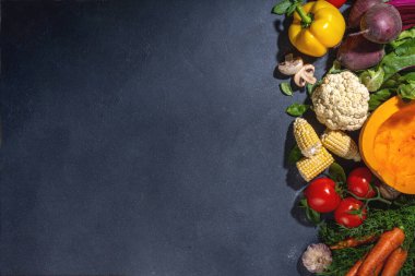 Autumn vegetables cooking background. Organic fall harvest farm vegetables, mushrooms. Various vegetarian ingredients set for cooking dinner on black kitchen background, top view copy space