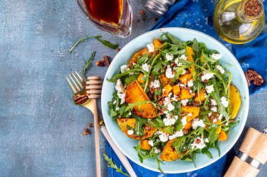 Sonbahar sıcak salatası. Ev yapımı sonbahar salatası ızgara ve fırında balkabağı roka, peynir ve ezilmiş fındık, vejetaryen paleo meyvesi ve sebze salatası fikri..