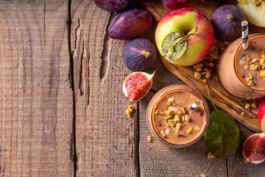 Sonbahar meyveli yoğurt içeceği. Taze meyve, erik, incir, elma, yulaf ve fındık, ahşap arka plan fotokopi alanı ile iki bardak çırpılmış meyve suyu.