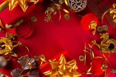 Çin Yeni Yıl 2024 tebrik kartı. Ejderha arka planında altın ejderha heykelciği, Çin fenerleri, geleneksel mücevherler, hediyeler, bozuk paralar, dilekleri olan kurabiyeler, kopyalama alanı olan parlak kırmızı Asya yılı.