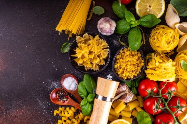 Baharatlı makarna ve yemek pişirmek için malzemeler. Hazırlık yemeği, öğle yemeği arkaplanı taze fesleğen, domates, baharat, sarımsak ve farklı çeşitte İtalyan Akdeniz makarnası.