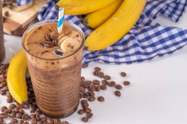 Karışık muzlu kahve. Soğuk latte kahve ve muzsuz süt, vejetaryen diyet içecek, donmuş muz ve espresso, beyaz mutfak masasında fotokopi alanı.