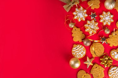 Noel, yeni yıl kurabiyeleri, kırmızı arka planda Xmas altın süslemeleri ve takıları olan zencefilli bisküviler. Üzerinde zencefilli kurabiye olan Noel tebrik kartı fotokopi alanı
