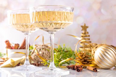 Noel süslemeli arka planda iki şampanya kadehi, Mutlu Noeller ve yeni yıl tebrik kartı geçmişi, altın takılar ve köknar ağacı dallarıyla