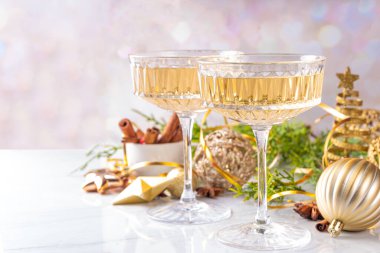 Noel süslemeli arka planda iki şampanya kadehi, Mutlu Noeller ve yeni yıl tebrik kartı geçmişi, altın takılar ve köknar ağacı dallarıyla