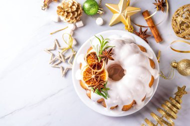 Noel pastası şekerli, portakallı ve biberiyeli. Geleneksel Noel ve yeni yıl pişirilmiş tatlı, vanilyalı meyveli kek, beyaz xmas süslemeli arka plan