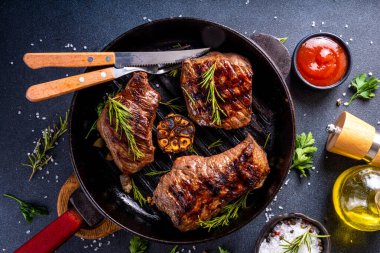 Grilled beef steak with herb and spices. Portion of fried meat cuts with rosemary, garlic, olive oil and ketchup sauce clipart