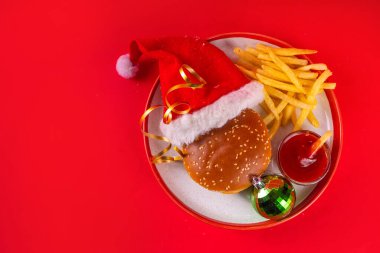 Noel burgeri ve patates kızartması teslimat menüsü. Patates kızartması ve ketçap soslu büyük bir çizburger. Noel bayramı ve yeni yıl dekorasyonu.