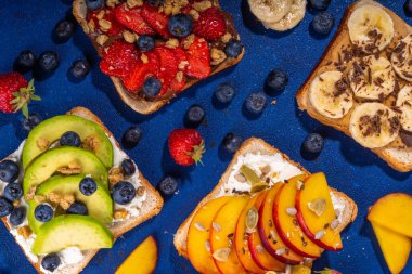 Meyveli sandviç. Fıstık ezmeli, krem peynirli çeşitli tostlar, yaz meyveleri ve meyveli çikolata - çilek, muz, şeftali, elma, yabanmersini, lezzetli öğle yemeği