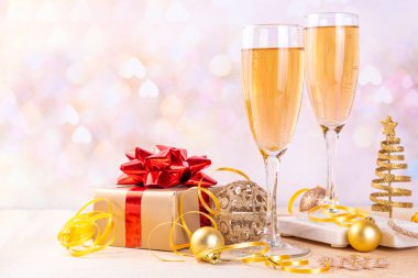 Yeni yıl partisi için şampanya. Noel, Noel, yeni yıl tebrik kartı arkaplanı, iki şampanya kadehi, hediye kutusu ve tatil süslemesi, Bokeh altın arka plan fotokopi alanı