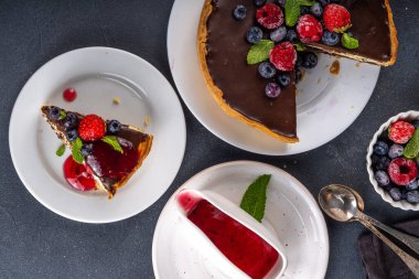 Çikolata ve çilekli ev yapımı cheesecake. Tatlı süzme peynirli pasta, taze ve çikolata soslu klasik tatlı, siyah beton masa fotokopisi alanı.