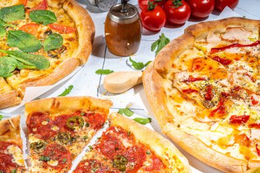 Evde ya da restoranda servis edilen üç çeşit pizza. İçinde pişirme malzemeleri, domates, fesleğen, ıspanak, roka klasik pepperoni pizza, vejetaryen sebze ve deniz ürünleri karidesli pizza var., 