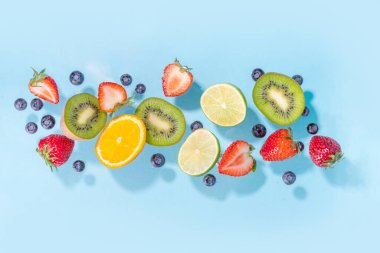 Yaz vitamini yiyecekleri, çeşitli meyveler, mango şeftali, şeftali, nane, kayısı, üzümlü üzümlü üzümlü üzümler, açık mavi arka planda uzanan kreatif düz fotokopi alanı.