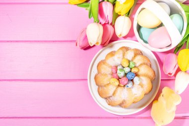 Geleneksel Paskalya yuvarlak pastası. Tatlı geleneksel Paskalya pişirmesi şeker tozu serpintileri, renkli Paskalya yumurtaları, bahar çiçekleri, pembe sarı renkli arka plan fotokopi alanı