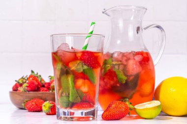 Sürahi ve bardakta ev yapımı çilekli limonata, bir sürü ezilmiş buz, dilimlenmiş böğürtlen ve nane yaprağı, donmuş çilekli sangria, buzlu çay, punç veya mojito ile.