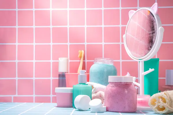 Bath background with cosmetics, cream, scrub, toothbrush, serum, mirror pink and blue tiled bright background. Cute bright self care, spa, relax, time for yourself concept.