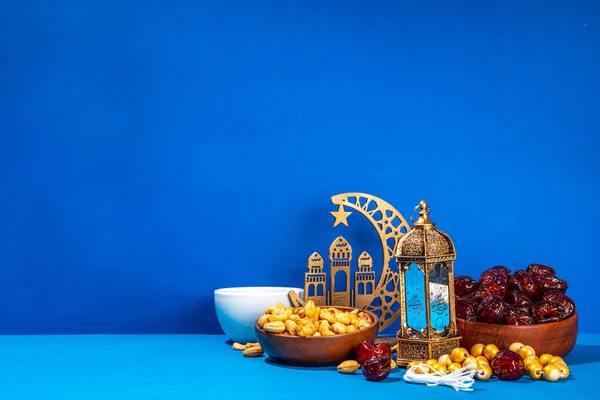 Ramadan muslim holiday background, with traditional treats - dates, nuts, dried fruits, sweets, religion rosary beads, lantern, tea, islamic Mosque, crescent moon Ramadan Kareem themed decorations