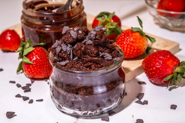 Edible brownie batter dough with chocolate chips and fresh strawberry. Two portioned small jars with raw edible chocolate cookie dough copy space