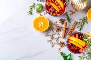 Geleneksel Noel aromalı şarap kokteyli, baharatlı kırmızı şarap içkisi, tarçın, portakal ve biberiye filizleri, Noel süslenmiş ahşap kaplama arka planda.