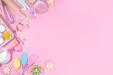 Cute pink sweet baking flat lay for Easter holiday. Cooking background with baking ingredients, rolling pin, whisk for whipping, cookie and cutters, sugar sprinkling, flour, top view copy space 