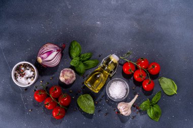 İtalyan yemekleri pişirmek için kullanışlı bir arka plan - domates, fesleğen yaprağı, yeşiller, zeytin yağı, tuz, biber, sarımsak, düz siyah beton masa üstü görünüm alanı 