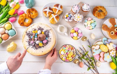 Easter brunch, breakfast food, Kids Easter party buffet. Various traditional Easter sweets, candy, pasties and baking - cross buns, cheesecake, chocolate eggs, pancakes, cupcakes, top view copy space