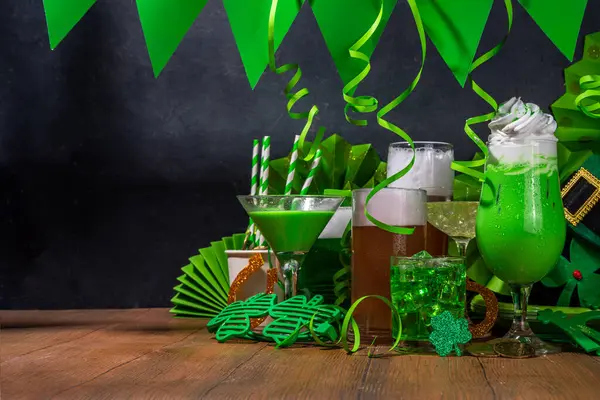 St Patrick\'s Day bar menu background. Set various golden, green beer glasses, different cocktails and drinks, with St. Patrick\'s Day party decor and accessories, on dark wooden background