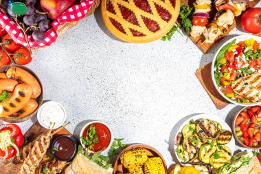 Çeşitli piknik barbekü yemekleri ve flatlay içiyorlar. Yaz bbq piknik yemekleri, ızgara etler, kebaplar, sebzeler, meyve salatası, geleneksel piknik pastası, sandviçler, üst görünüm fotokopi alanı.