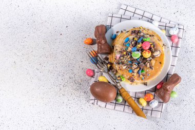 Paskalya için çocukların komik şirin kahvaltısı. Amerikan gözlemeleri, çikolatalı kızarmış hamur kekleri, çikolatalı yumurtalar, marşmelovlar, üzerine çikolata parçacıklı şeker serpiştirilmiş dekorlar.