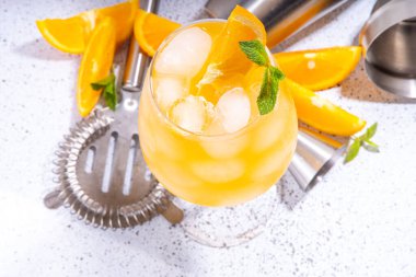 Portakal ve nane alkollü kokteyl, aperol spreyi, uzun kokteyl bardağında mimoza içeceği, taze portakal dilimli garnitür, bar kaplamalı beyaz kaplama, kopyalama alanı.