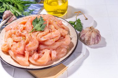 Diyet beyaz kümes hayvanlarını pişirmek. Taze dilimlenmiş tavuk şeritleri pişirmek için, baharatlar, otlar, beyaz fayansların arka planında fotokopi alanı