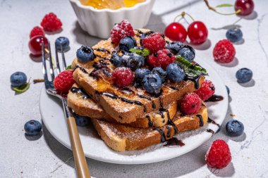 Summer breakfast with french toast. Baked with toasts with berries (blueberries, strawberries) and honey, traditional morning sweet dessert with fresh ripe berry