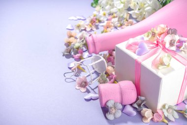 Cute high-colored Valentine day background, with pink colored champagne bottle, spring blossom flowers, little heart decor, on violet very peri color background flatlay copy space