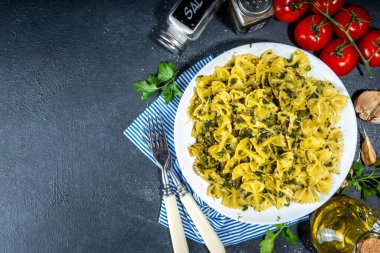 İtalyan Akdeniz yemek konsepti. Ispanaklı, mantarlı, sebzeli ve kremalı makarna. Siyah beton masanın üzerinde, akşam yemeği için baharatlar var.