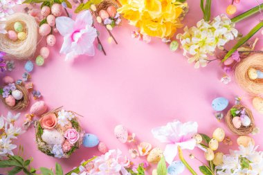 Spring Easter holiday top view flat lay background with eggs in nests and flowers. Happy Easter  greeting card background with copy space, on pastel pink background copy space