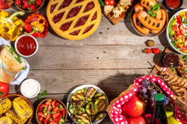 Çeşitli piknik barbekü yemekleri ve flatlay içiyorlar. Yaz bbq piknik yemekleri, ızgara etler, kebaplar, sebzeler, meyve salatası, geleneksel piknik pastası, sandviçler, üst görünüm fotokopi alanı.