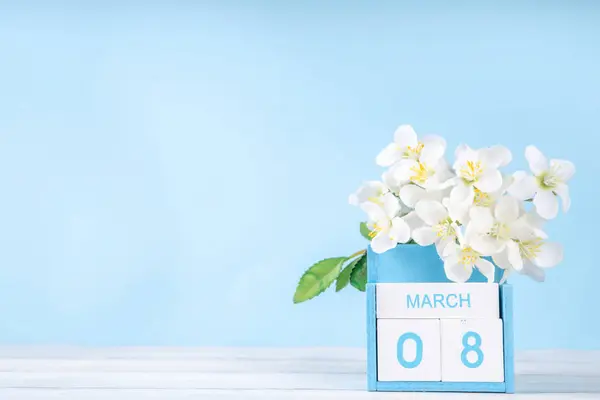 Spring holiday background with wooden calendar and spring blossom flower on light blue background copy space