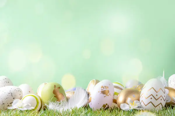 Easter egg and grass background. Funny colorful Easter eggs with bunny rabbit decor and sunny bokeh on grass and light green background. Happy Easter spring holiday greeting card background