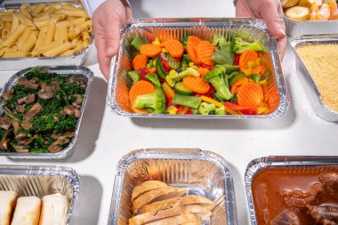 Yemek pişirme konsepti. Çeşitli çeşit mezeler: tahıl gevreği, makarna, makarna, pişmiş ve taze sebzeler, et, tavuk, nugget, kahvaltı krepleri ve yiyecek kabında meyve. 