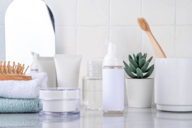 Skinimalizm, cilt minimalizmi cilt bakımı jölesi, güneş koruma kremi, serum şişeleri ve kavanozlarla minimum beyaz banyo arka planında fotokopi alanı