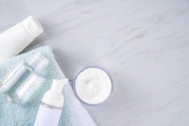 Skinimalizm, cilt minimalizmi cilt bakımı jölesi, güneş koruma kremi, serum şişeleri ve kavanozlarla minimum beyaz banyo arka planında fotokopi alanı