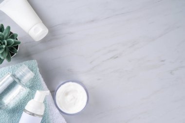 Skinimalizm, cilt minimalizmi cilt bakımı jölesi, güneş koruma kremi, serum şişeleri ve kavanozlarla minimum beyaz banyo arka planında fotokopi alanı