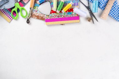 Dikiş dikme, dikiş ve giysi onarımı, arka plan, koleksiyon defteri, yorgan dikme. Renkli kumaş, makas, cetvel, dikiş araçları, iğneler, iplikler beyaz masa arkaplanındaki üst görünüm kopyalama alanı