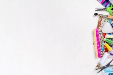 Dikiş dikme, dikiş ve giysi onarımı, arka plan, koleksiyon defteri, yorgan dikme. Renkli kumaş, makas, cetvel, dikiş araçları, iğneler, iplikler beyaz masa arkaplanındaki üst görünüm kopyalama alanı