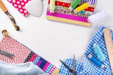 Dikiş dikme, dikiş ve giysi onarımı, arka plan, koleksiyon defteri, yorgan dikme. Renkli kumaş, makas, cetvel, dikiş araçları, iğneler, iplikler beyaz masa arkaplanındaki üst görünüm kopyalama alanı