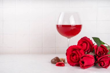 Kırmızı güller, şarap, hediye kutusu ve çikolatalı şekerlerle dolu sevgililer günü arkaplanı.