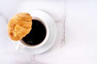 Kruvasan ve kahve çekirdekli sade espresso kahve fincanı, basit geleneksel Fransız kahvaltısı.