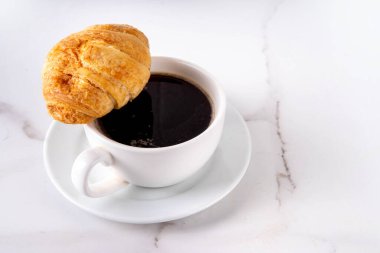 Kruvasan ve kahve çekirdekli sade espresso kahve fincanı, basit geleneksel Fransız kahvaltısı.