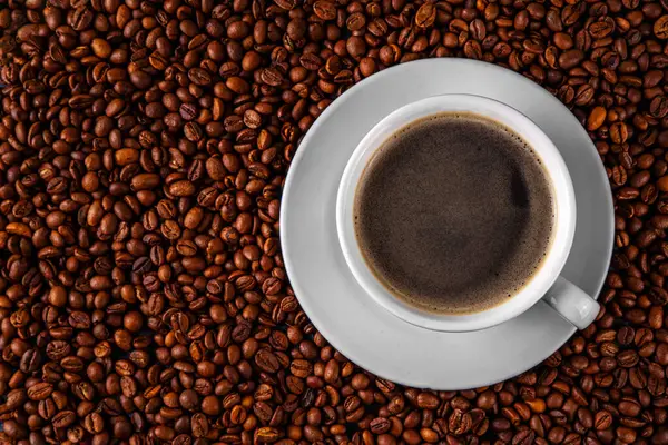 Kruvasan ve kahve çekirdekli sade espresso kahve fincanı, basit geleneksel Fransız kahvaltısı.